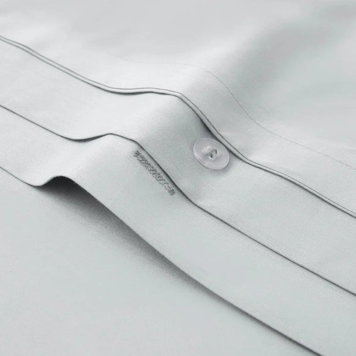 Close-up of a light gray bedding fabric with a button