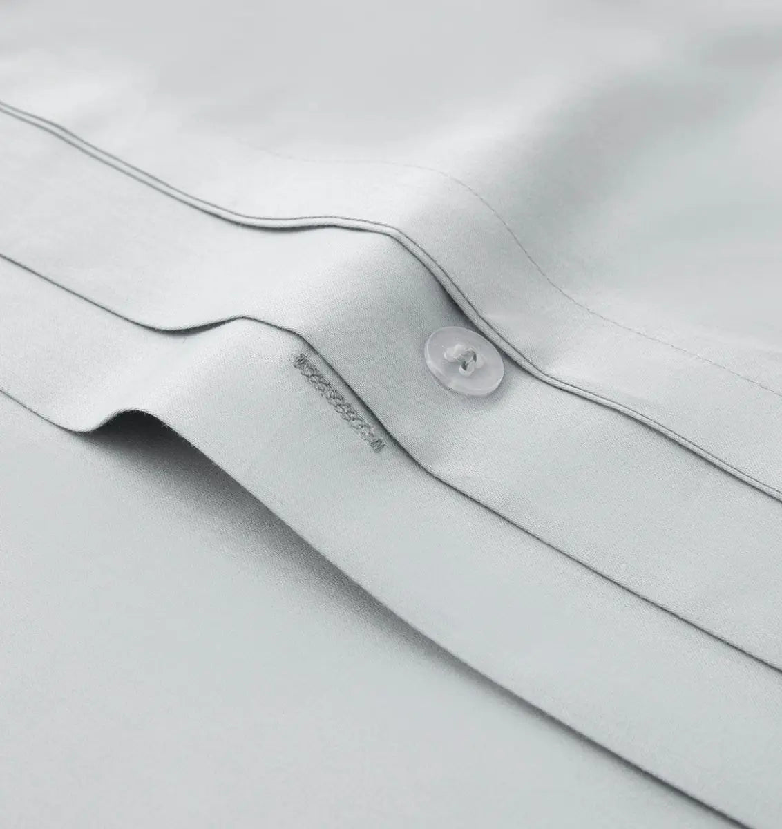 Close-up of a light gray bedding fabric with a button