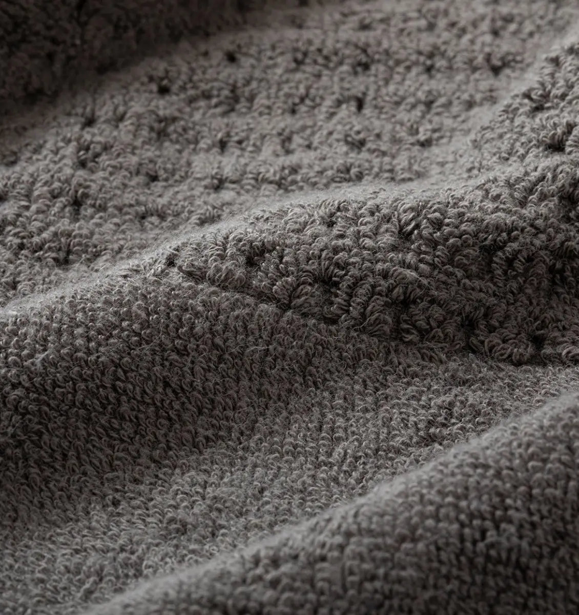 Close-up of textured gray waffle towel fabric with a focus on pattern and texture.