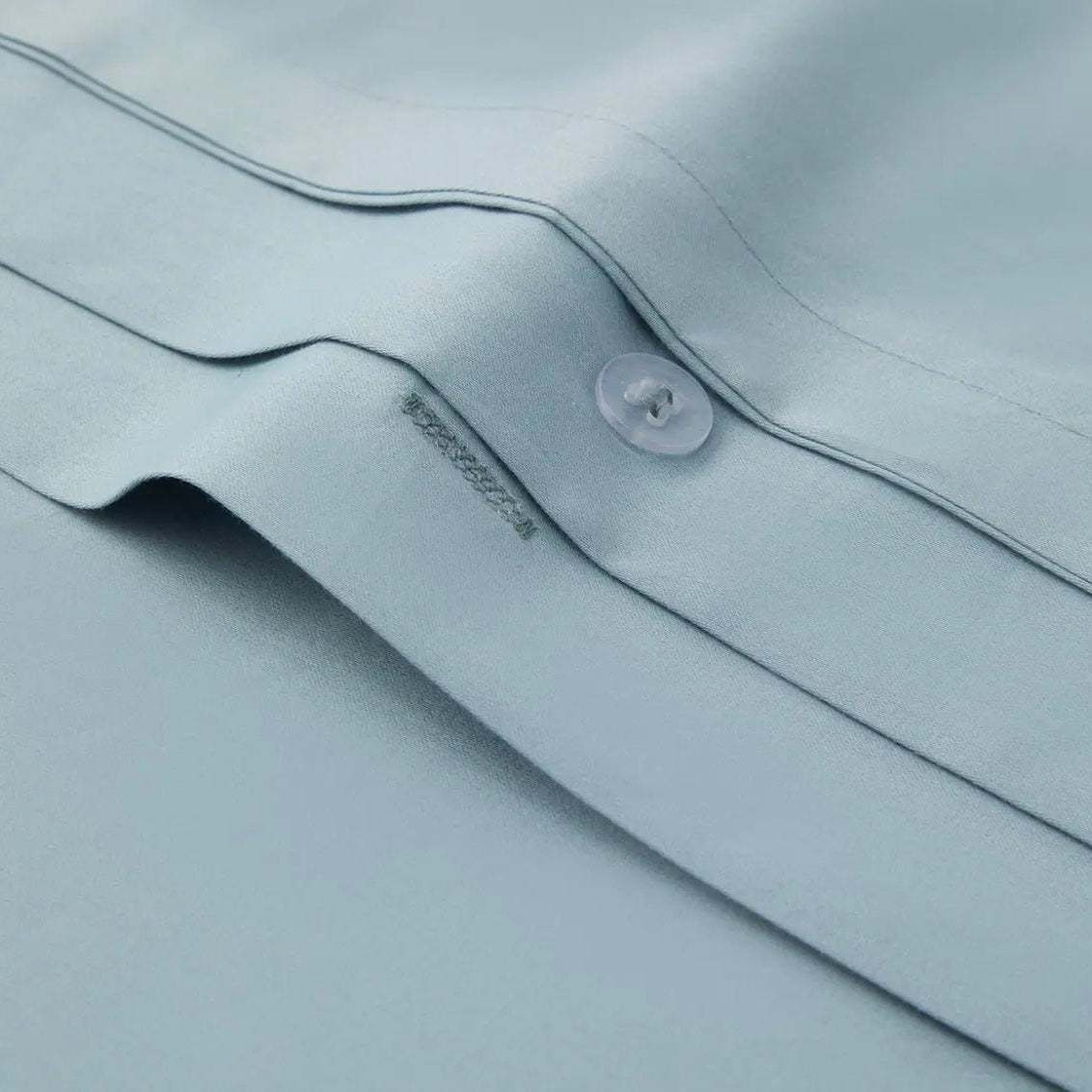 Close-up of a light blue bedding fabric with a button