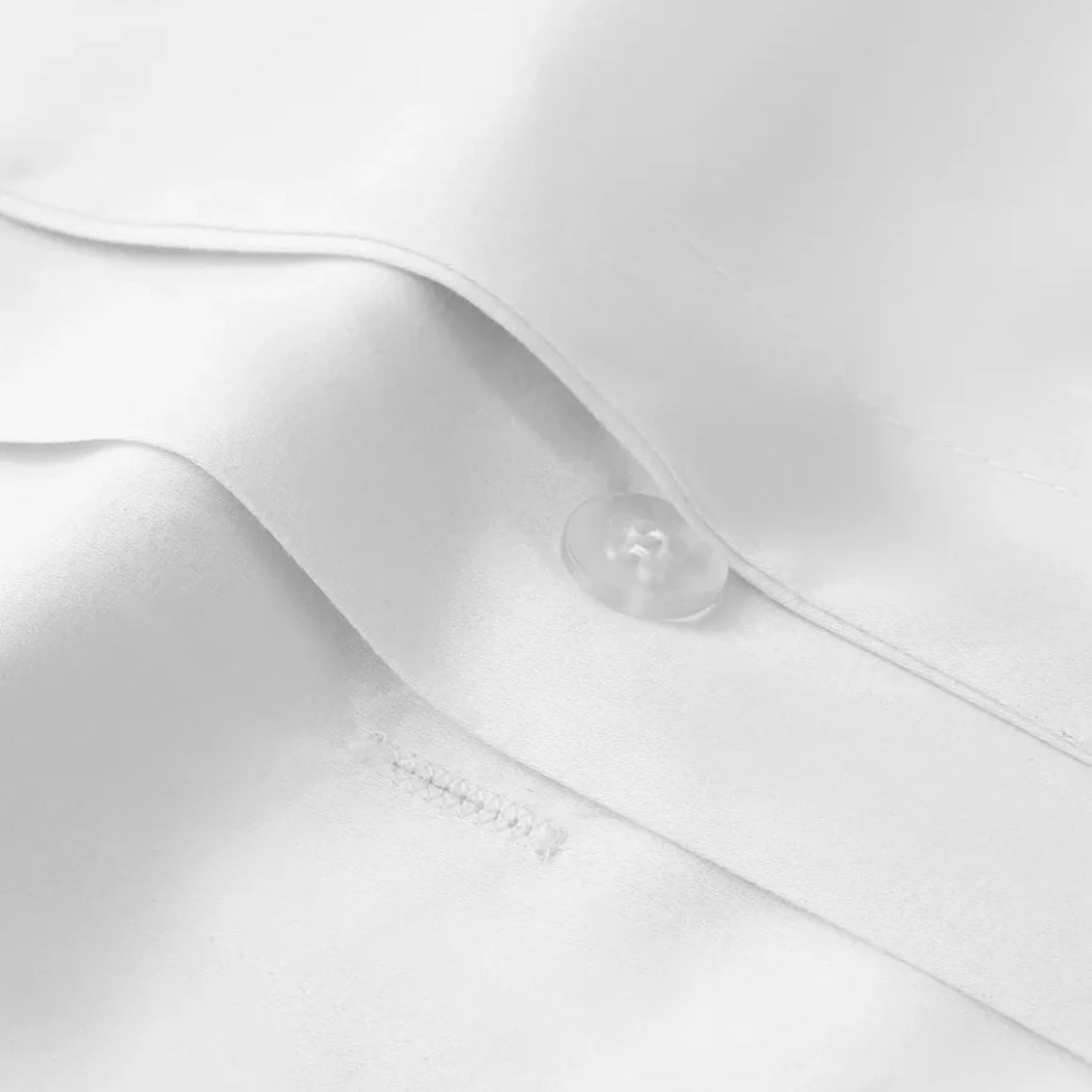 Close-up of a white bedding sheet with a button