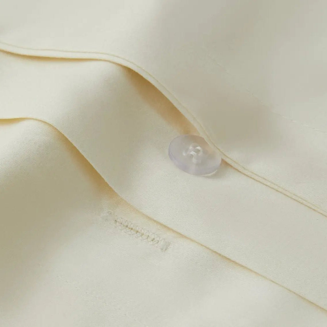 Close-up of a button on an ivory bedding fabric