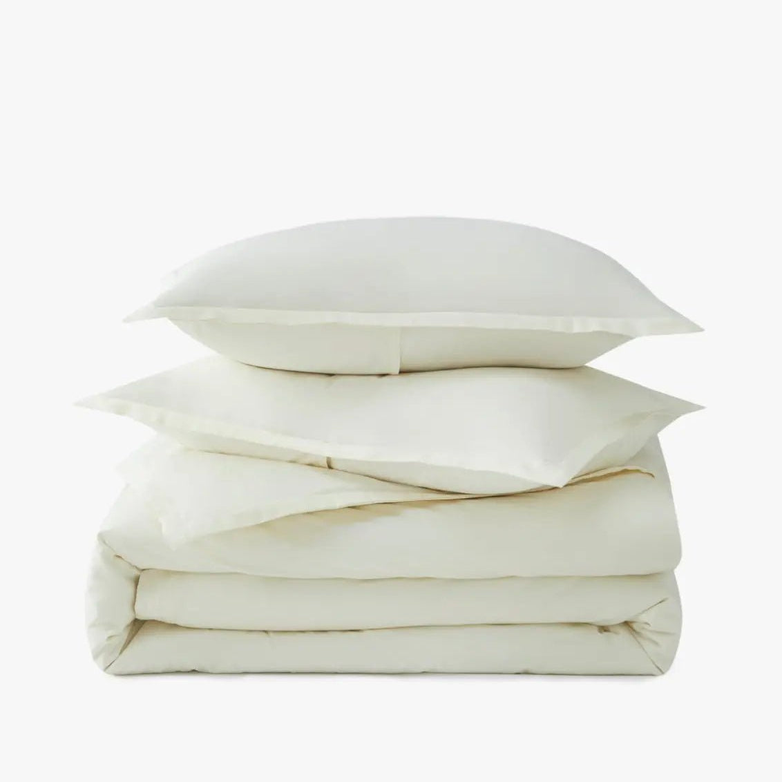 Stack of ivory pillows and duvet on a white background