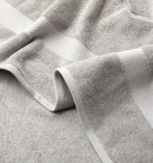 Close-up of a textured Premium Turkish Cotton gray towel with folds on a light gray background