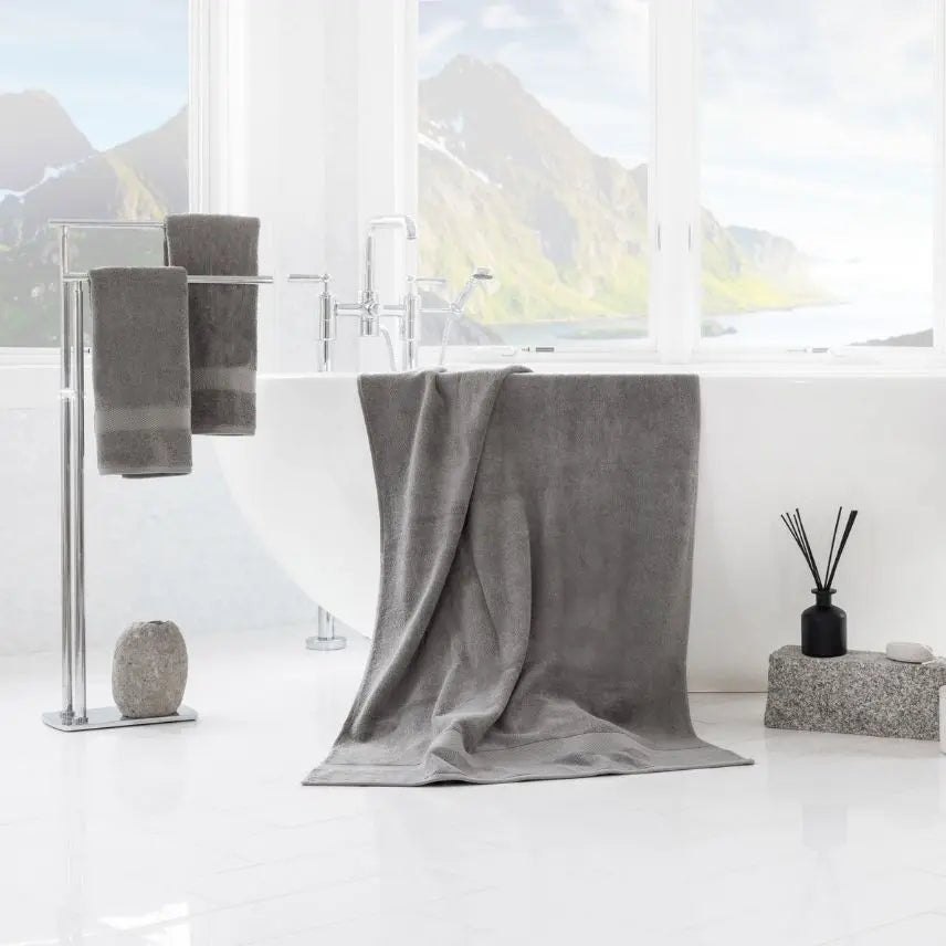 Premium Turkish Cotton Gray towel draped over a bathtub with a scenic view outside the window.