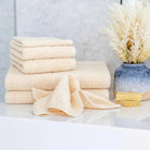 Stack of cream towels on a white bathroom surface with a decorative blue vase in the background.