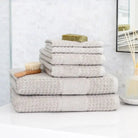 Stack of pale gray towels stacked in a bathroom surface with brush and soap on top