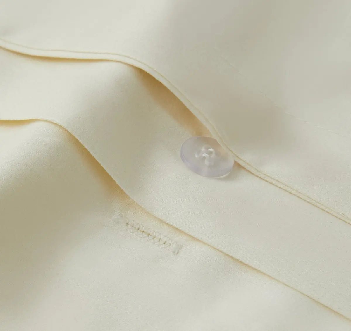 Close-up of a button on an ivory bedding fabric 