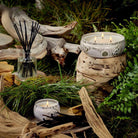 Voluspa Santal Vanille Reed Diffuser and Candles on a wood and grass scenery