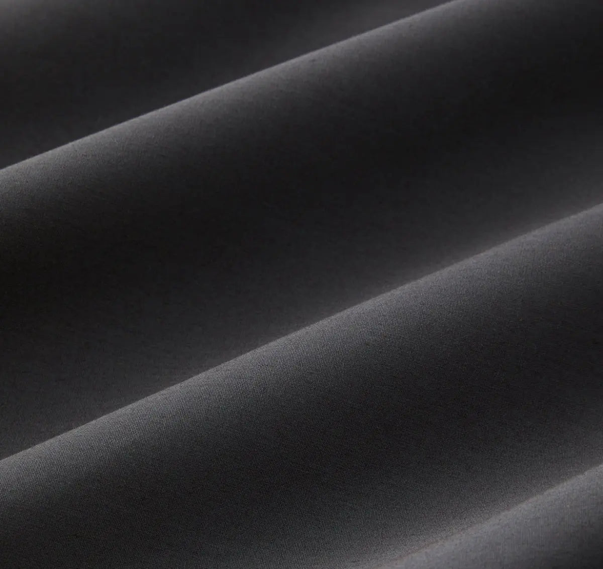 Close-up of slate gray bed sheet fabric with folds