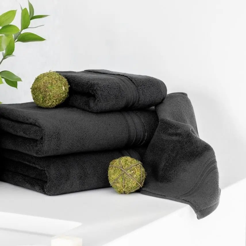 Stack of coal dark gray towels with green spherical objects on a white bathroom 
surface