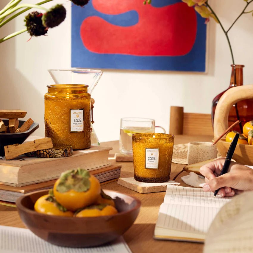 Table scenery of a hand writting on a notebook. Table decor includes Voluspa candles and a fruit basket decoration. 
