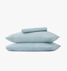 Set of light blue pillowcases and bed sheets on a white background