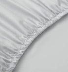 Close-up of a fitted sheet on a bed with a plain background
