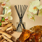 Voluspa Baltic Amber Diffuser surrounded by amber rocks, flowers, and wood chips.
